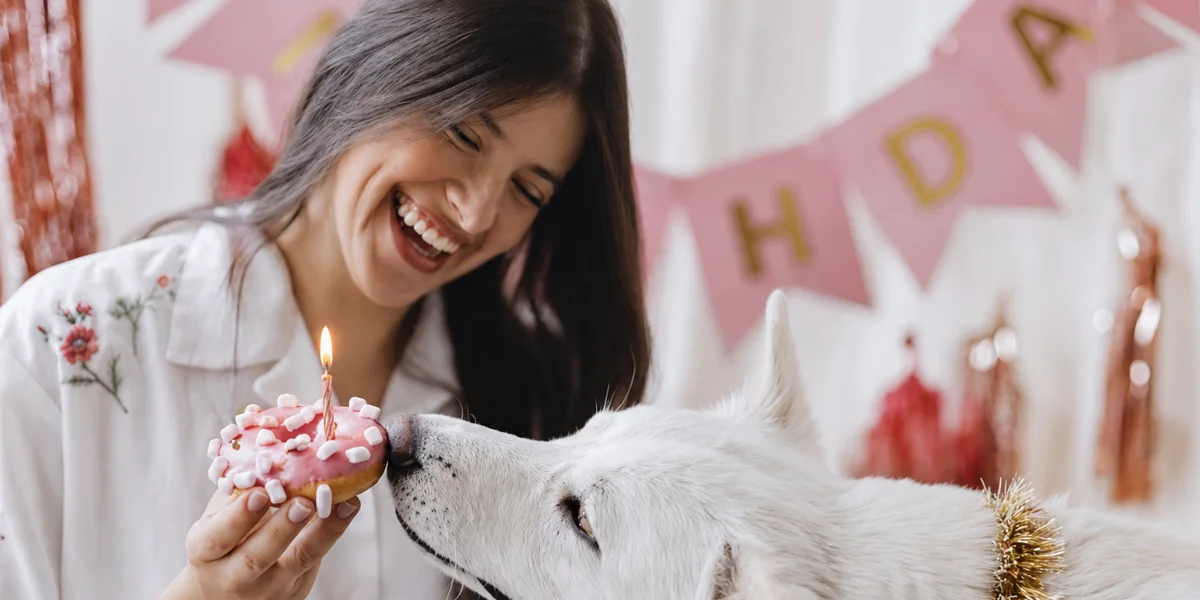 A joyful dog parent celebrating with her dog and a fresh DogBake treat